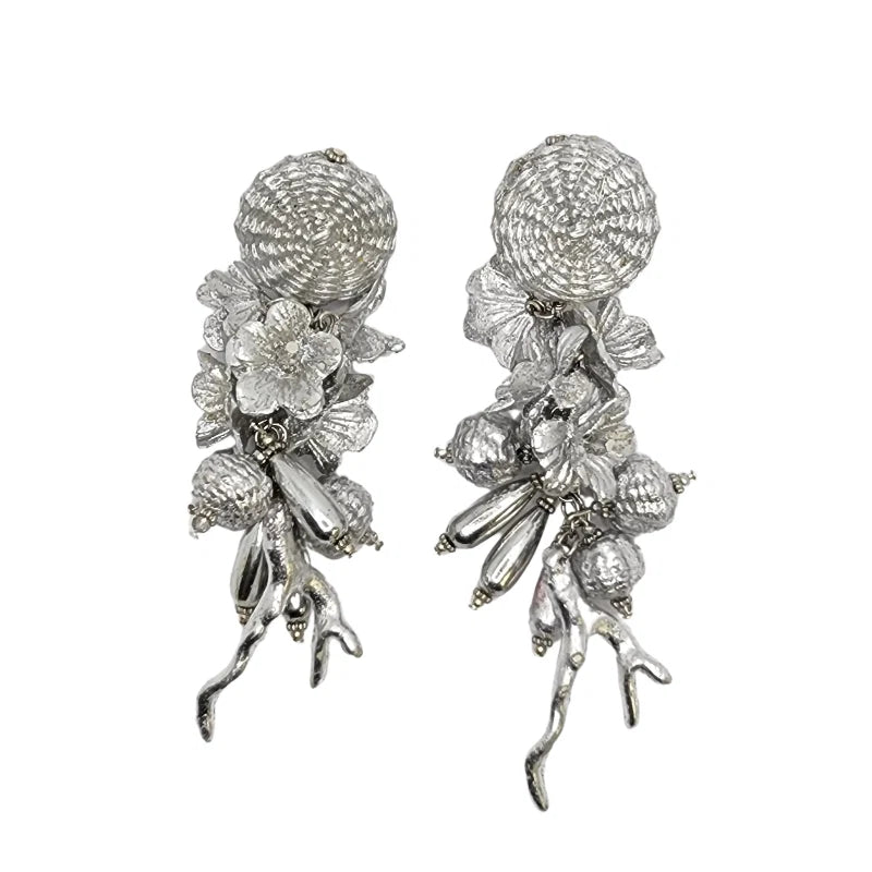 These handcrafted earrings are made from banana fiber painted in silver, delicately adorned with flower embellishments.