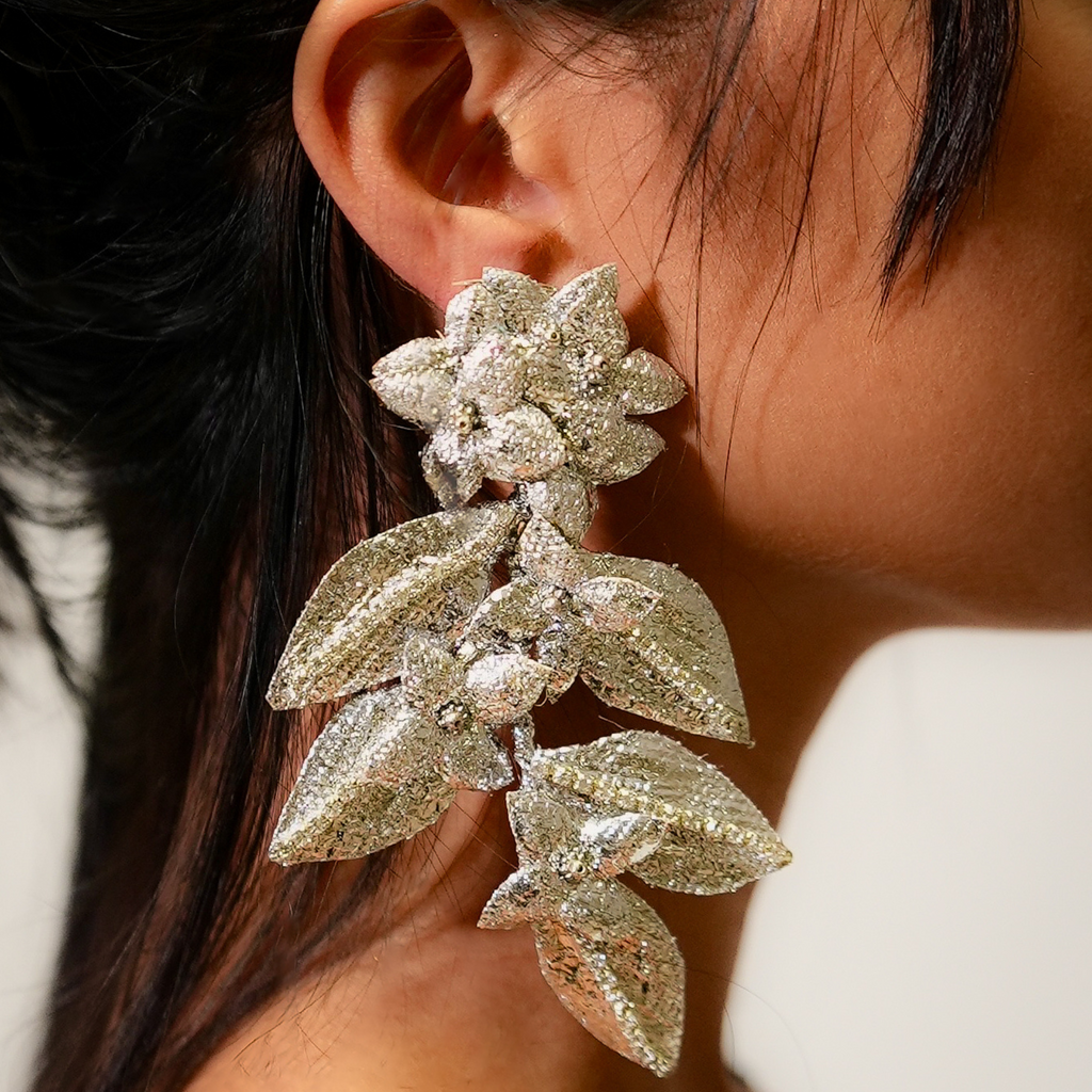 Close-up of a person wearing a sparkling floral earring.