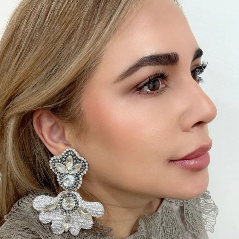 The Radiant Fleur Earrings showcase a stunning half-circle design crafted with golden accents and adorned with sparkling crystal gemstones. 
