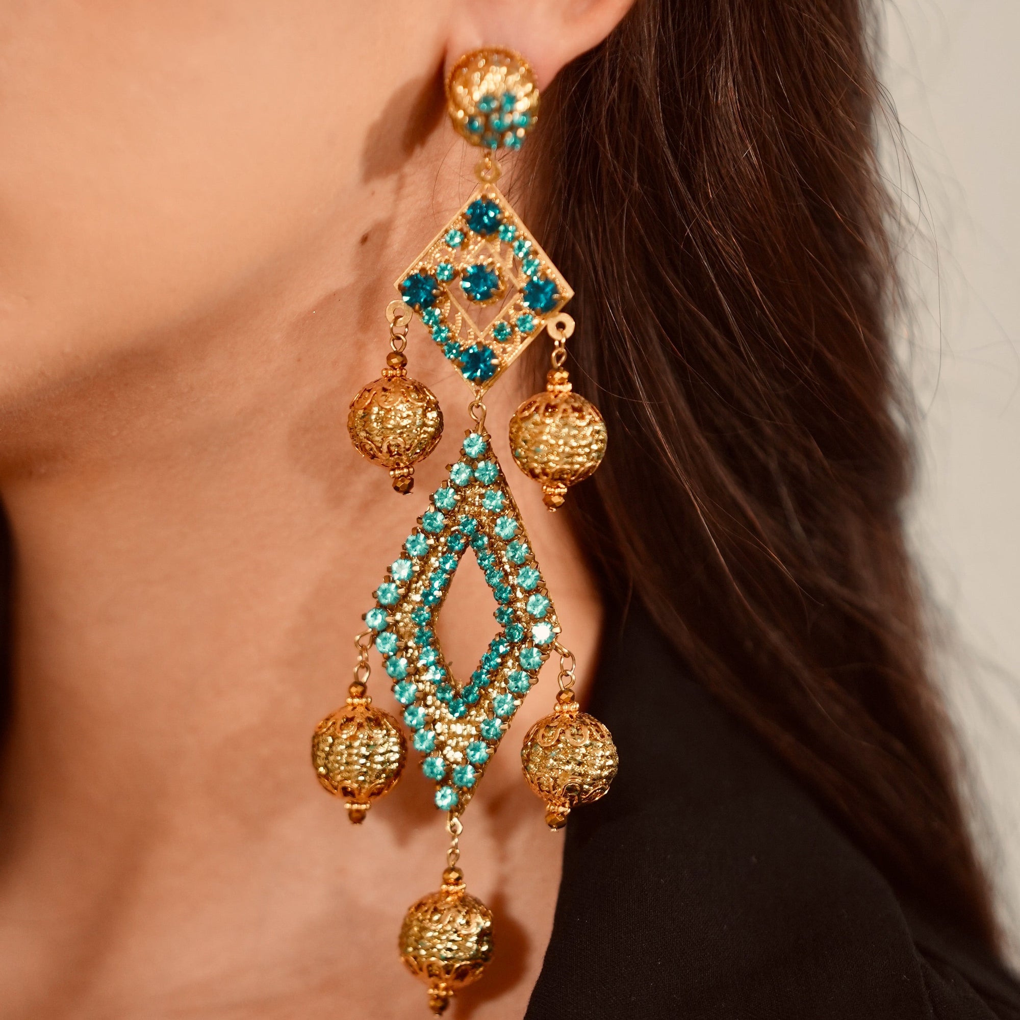 Close-up of a person wearing gold and turquoise earrings.