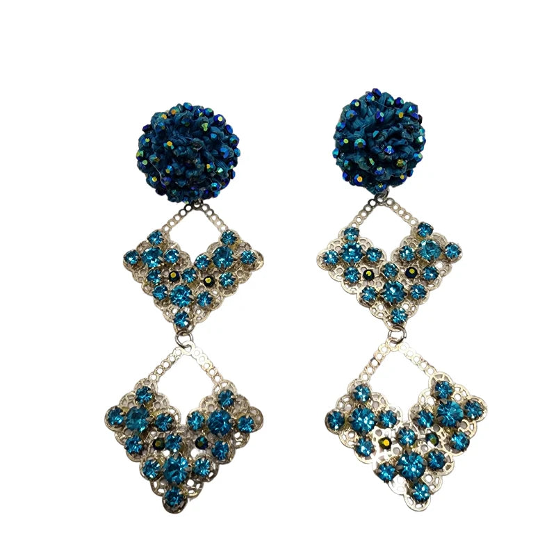 Handmade silver diamond-shaped earrings with vibrant blue gemstones and blue pom-pom tops