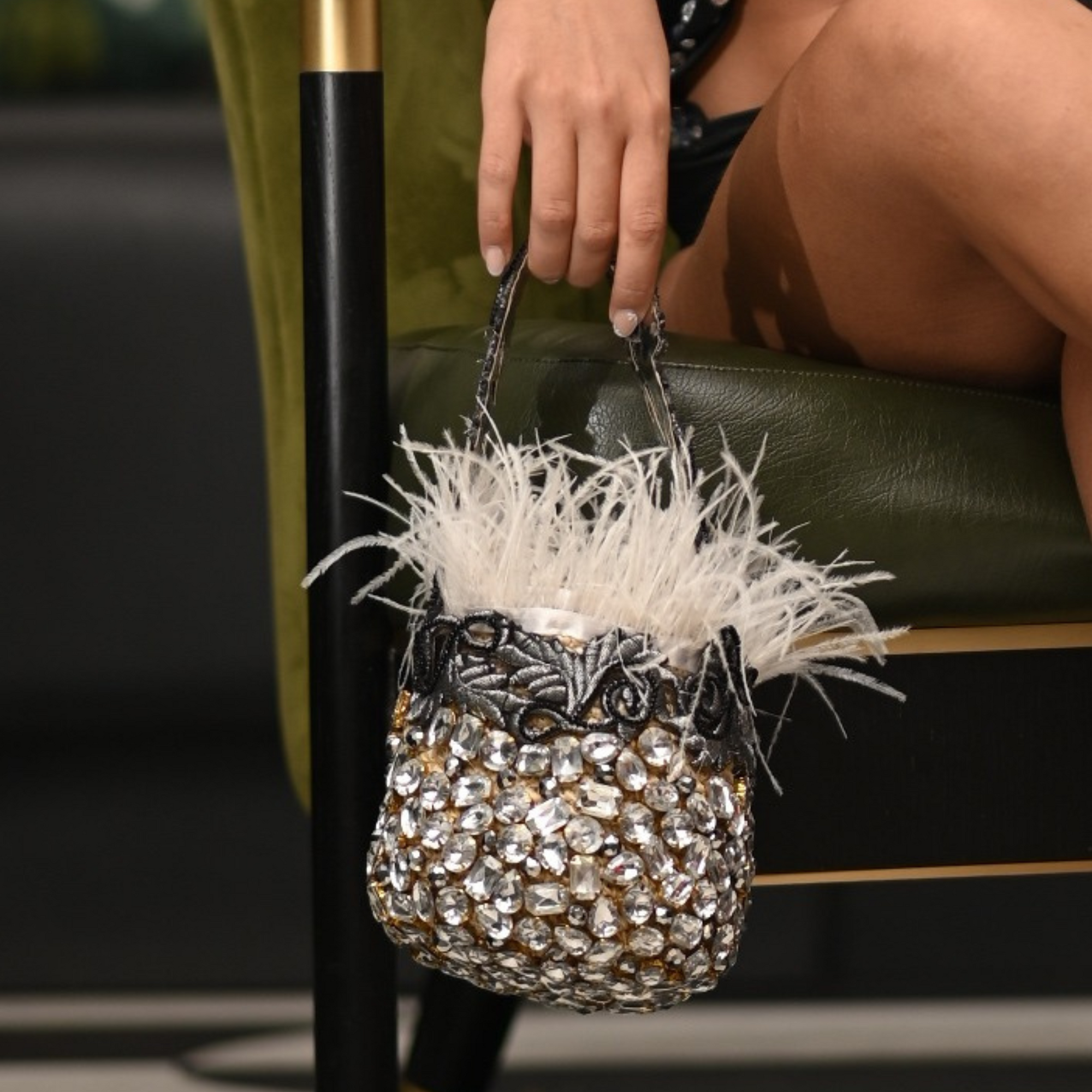 Woman holding the White Crystal Feather Bag while seated, showcasing its luxurious texture and sparkling details.