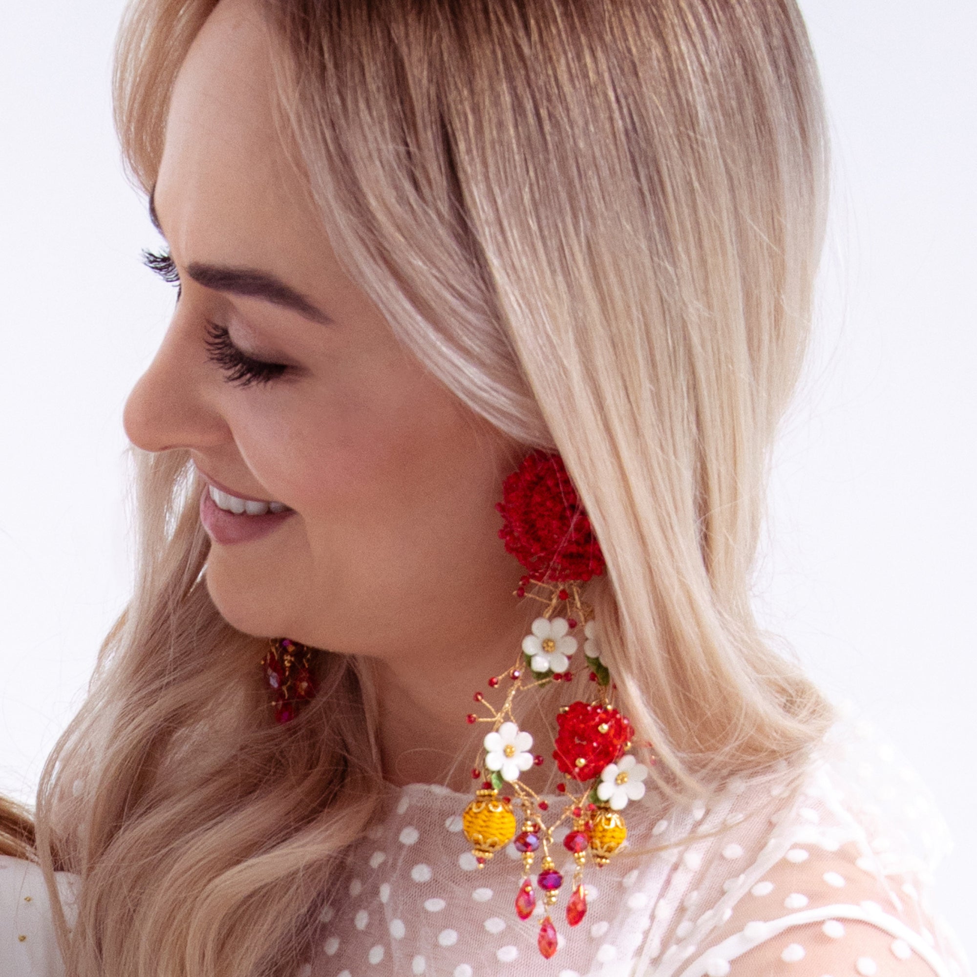 Woman wearing colorful floral earrings with a white background