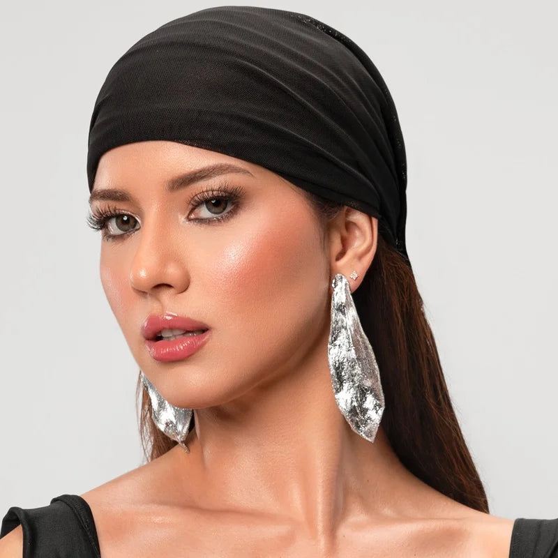 Close up of a woman wearing silver leaf shaped earrings.