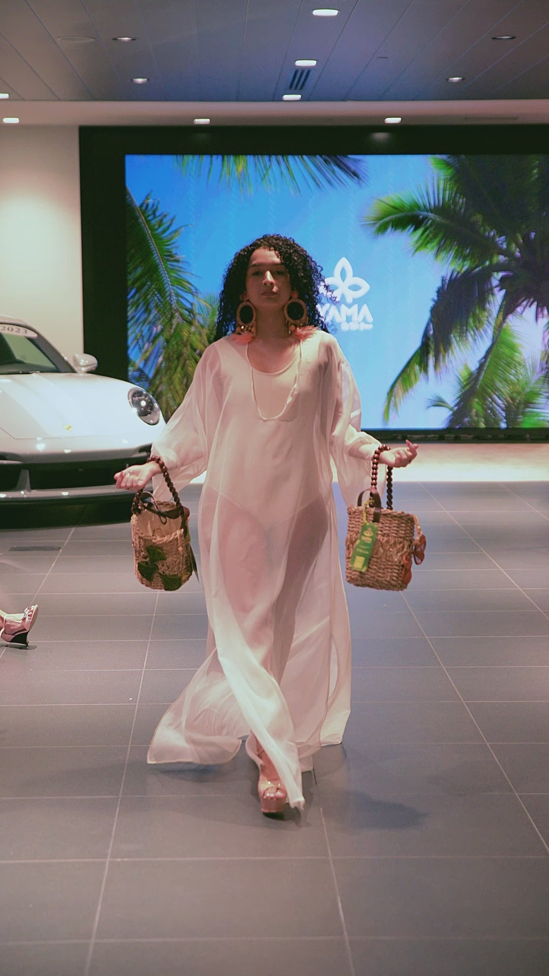 Runway model showcasing Bucket Flower Bags in green and orange flower variations, handcrafted with wooden handles and natural fiber body
