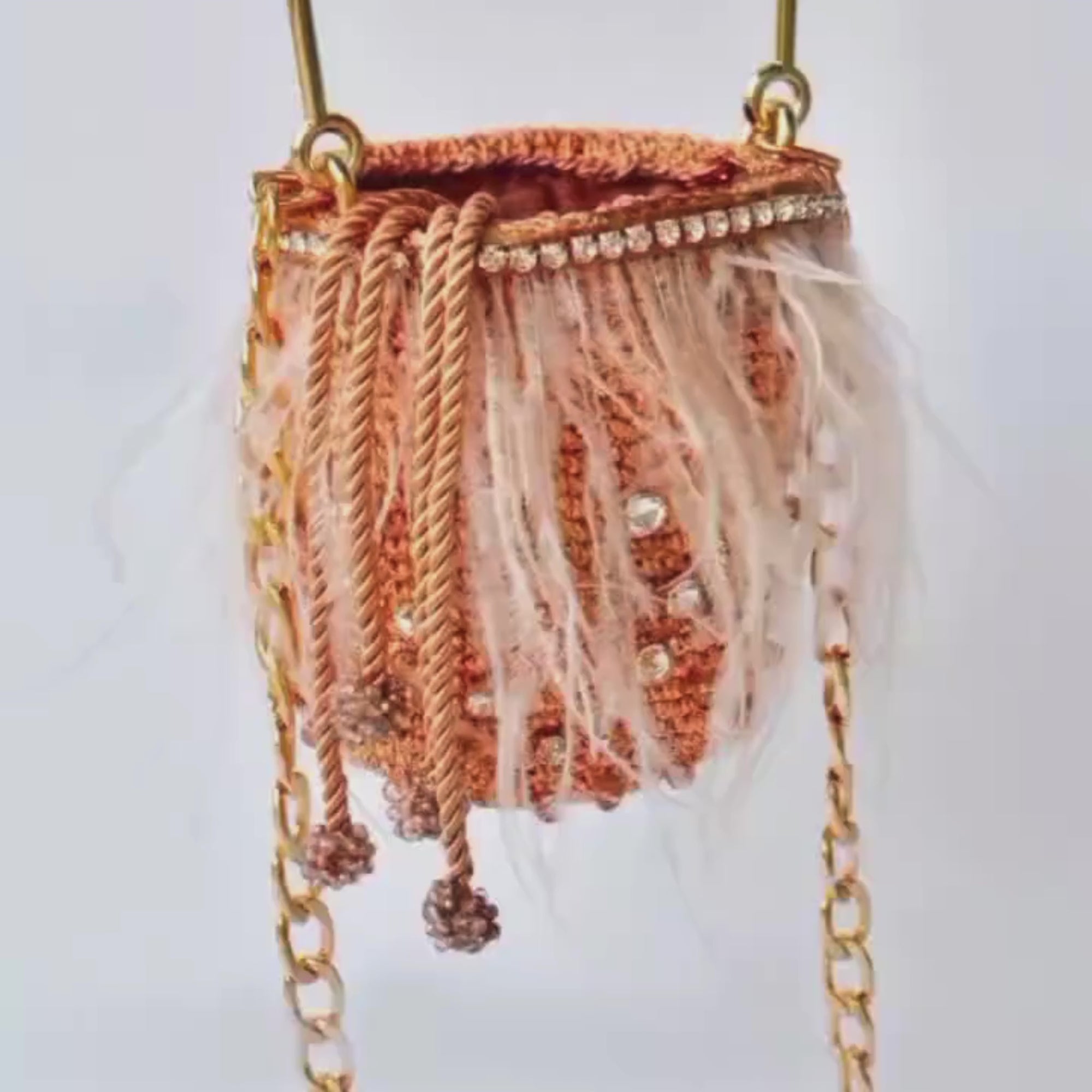 Rotating view of a rose gold bag with white feathers and gold chain strap, showing details from different angles